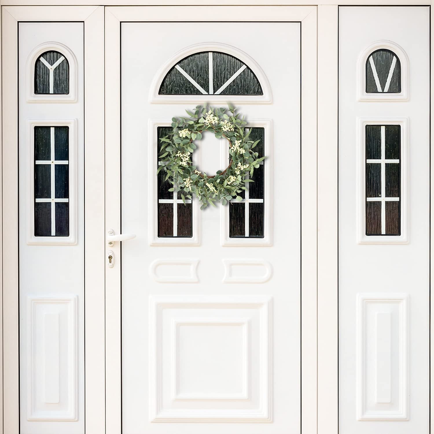 Eucalyptus wreath with white berries hanging on a white double door