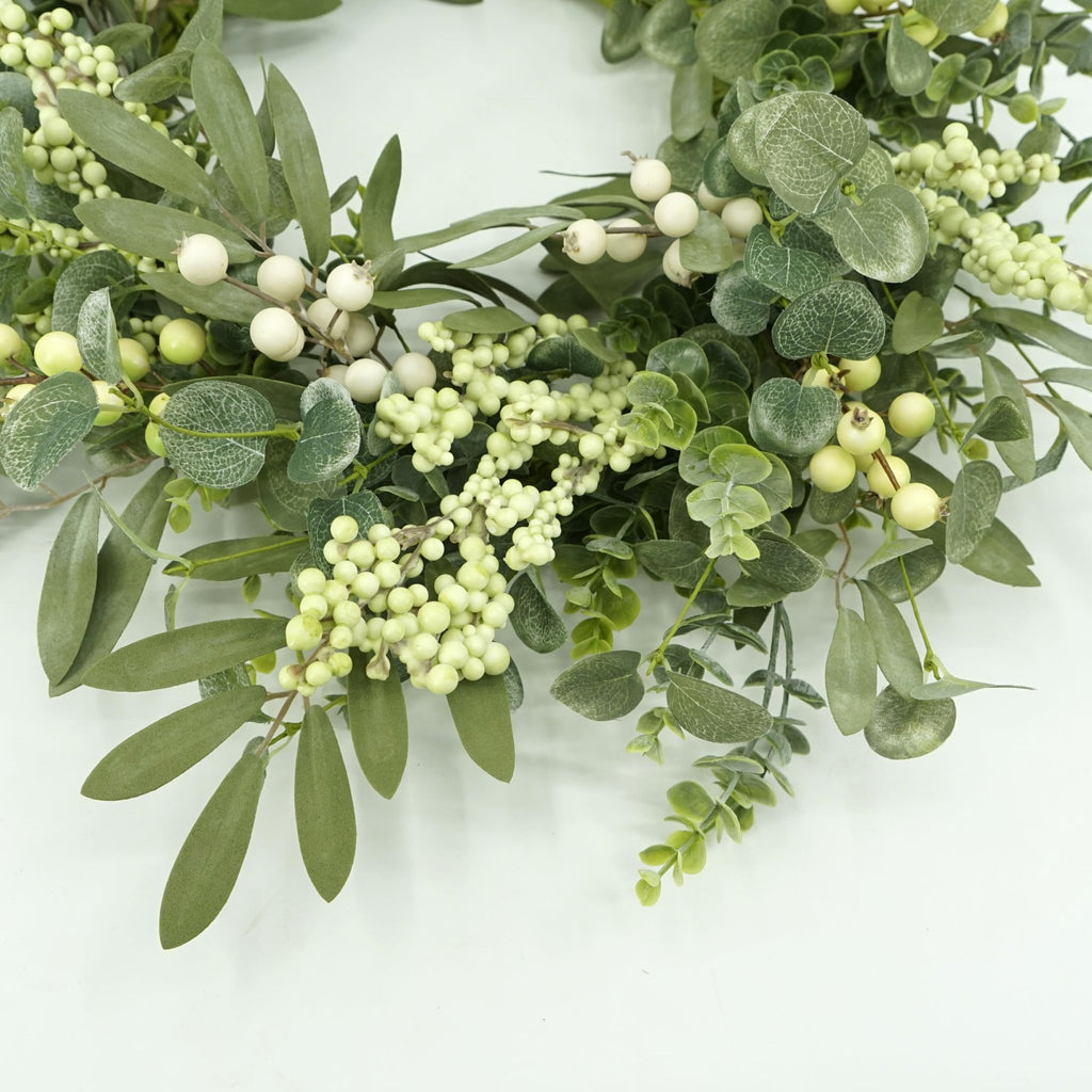 Close-up of a 20-inch artificial wreath with eucalyptus leaves, olive leaves, and white berries on a white background.