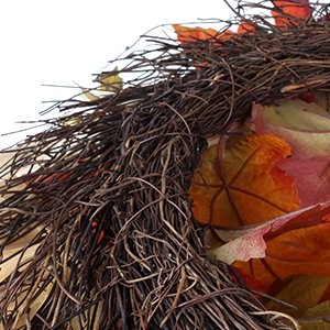 Close-up of a fall wreath with grapevine base, autumn leaves, pumpkins, berries, and pine cones.