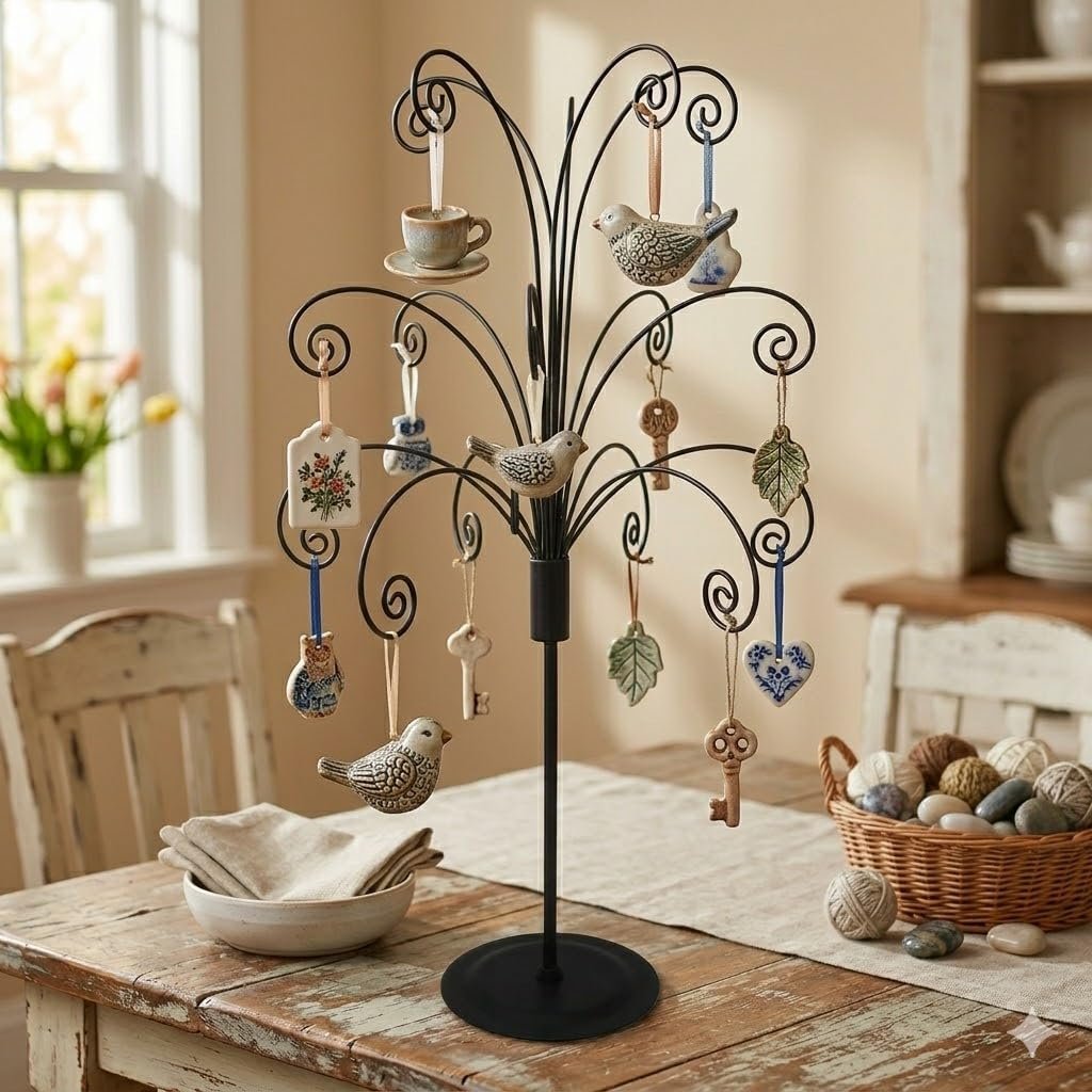 Black metal ornament display stand with various hanging ornaments including birds, keys, and hearts, set on a wooden table.