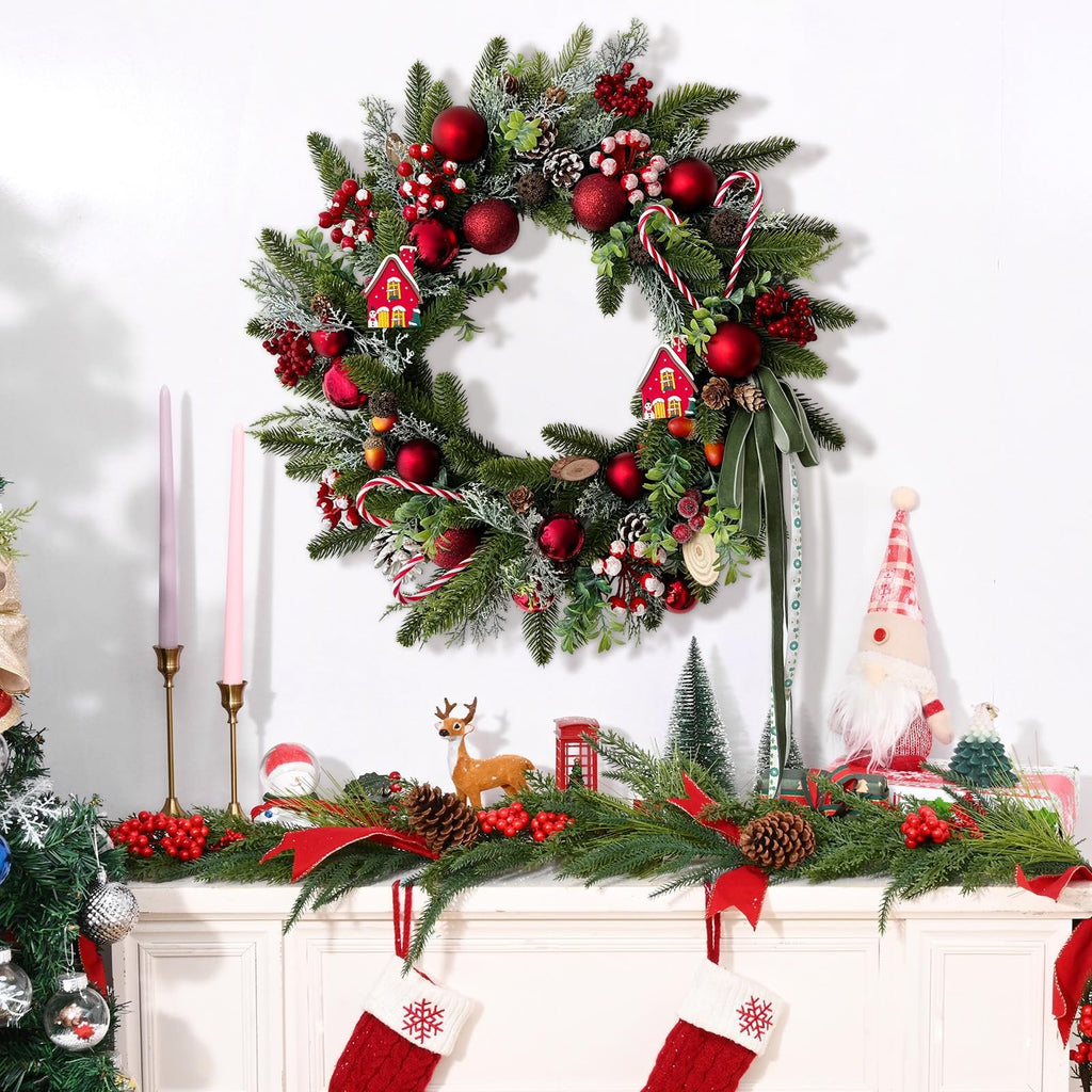 Festive Christmas wreath with red ornaments, pine cones, berries, candy canes, and small houses, displayed above a mantelpiece with garland and stockings.