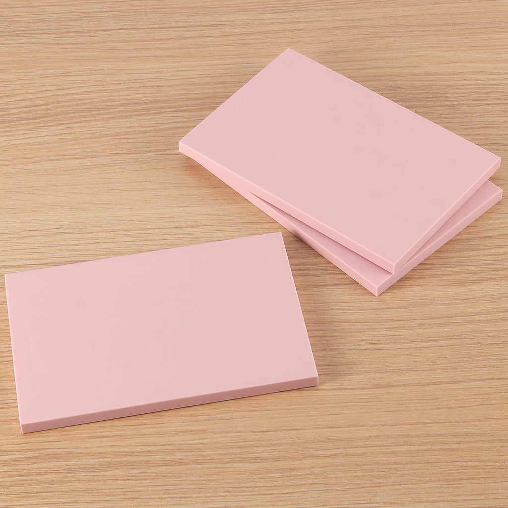 Three pink rubber carving blocks for stamp making on a wooden surface, angled view.