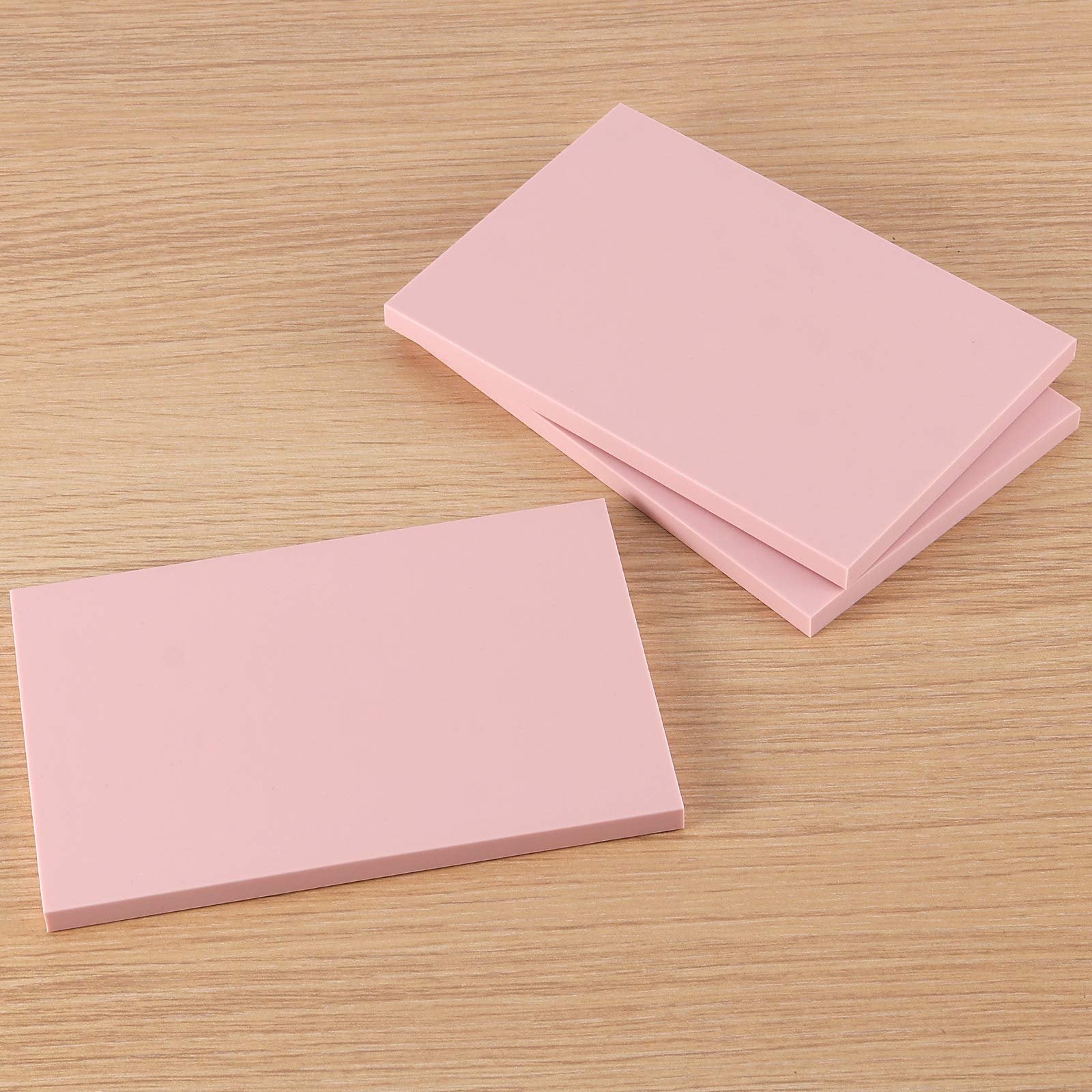 Three pink rubber carving blocks for stamp making on a wooden surface, angled view.