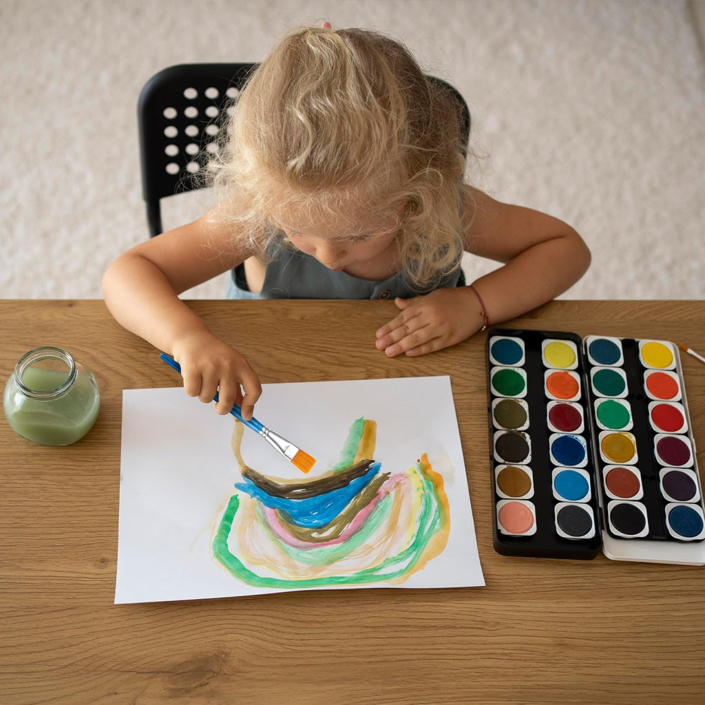 Young child painting a colorful abstract picture with watercolors and a paintbrush.