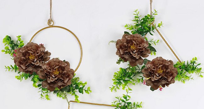 Two artificial peony floral arrangements on gold geometric frames, one circular and one triangular, against a white background.
