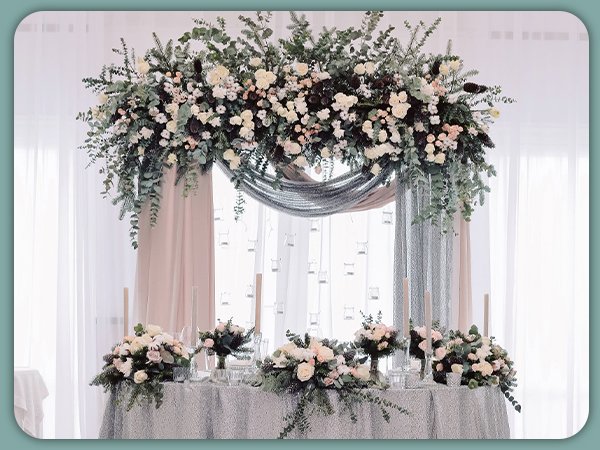 Wedding reception table decorated with floral arrangements and draped fabric.