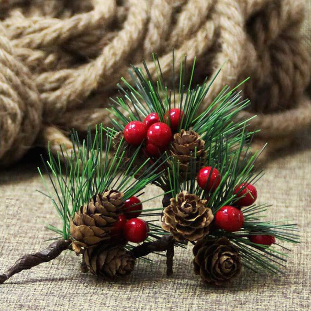 Artificial pine pick with red berries and pinecones on a textured background with rope