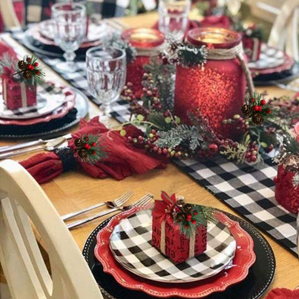 Christmas table setting with pine picks, red berries, pinecones, candles, and plaid accents
