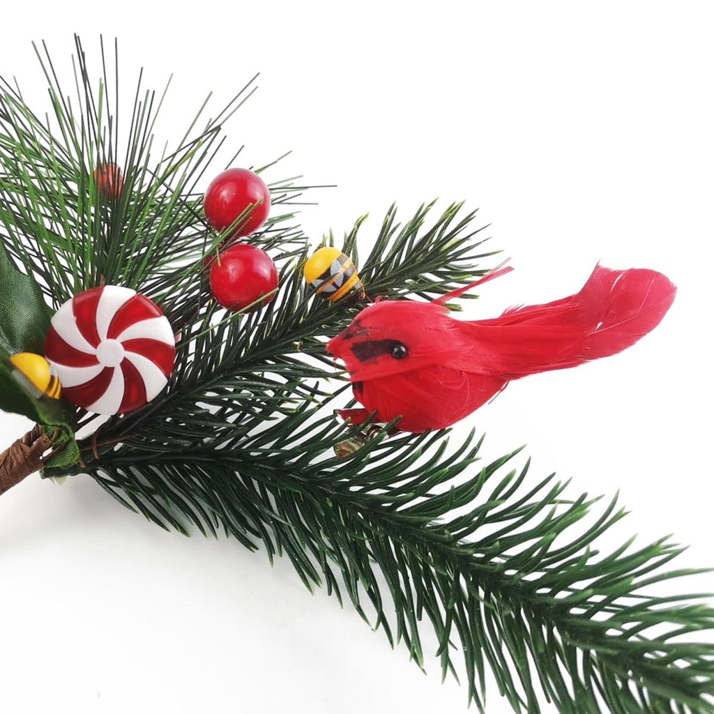 Christmas cardinal ornament with candy and berries on pine branch, close-up view