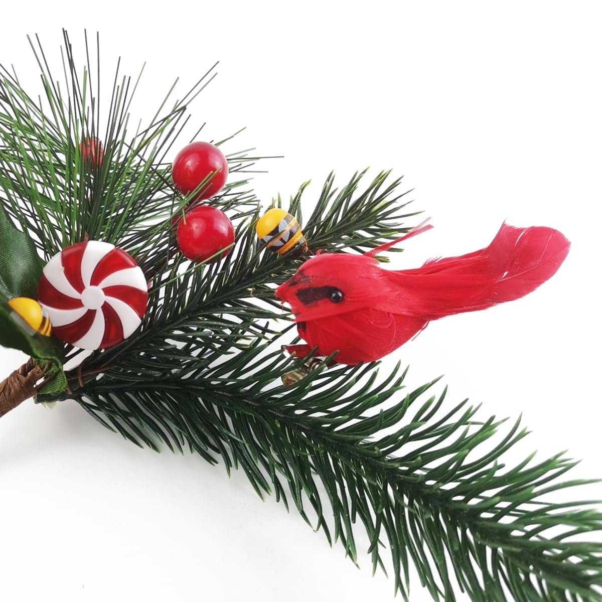 Christmas cardinal ornament with candy and berries on pine branch, close-up view