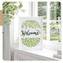 Plastic stencil with 'Welcome' text and green leaf design, displayed on a windowsill.