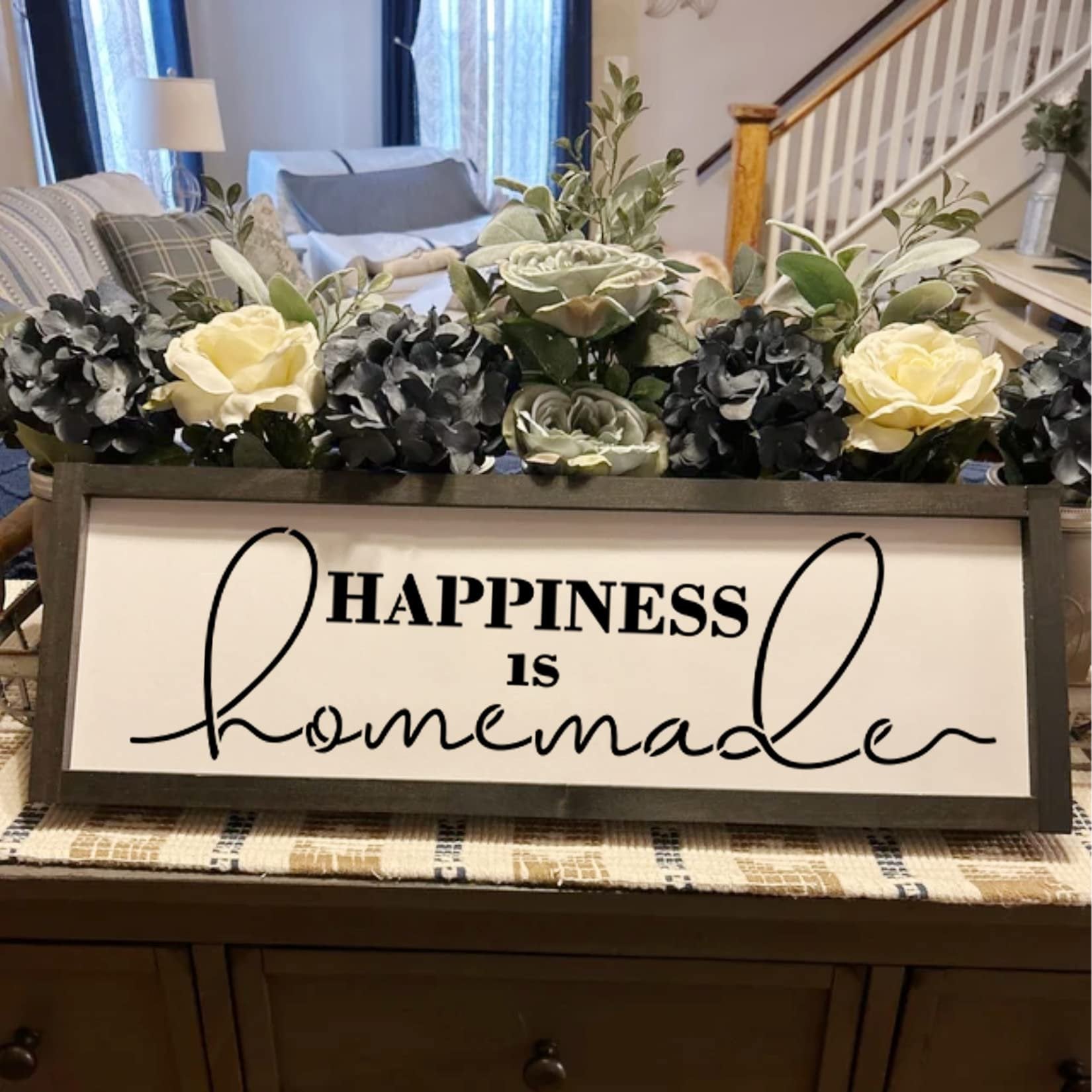 Farmhouse sign with floral arrangement reading "Happiness is Homemade" displayed on a dresser.