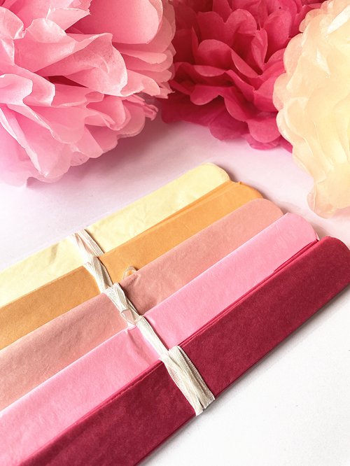 Pink mix tissue paper pom poms and folded tissue paper sheets in various shades of pink and yellow