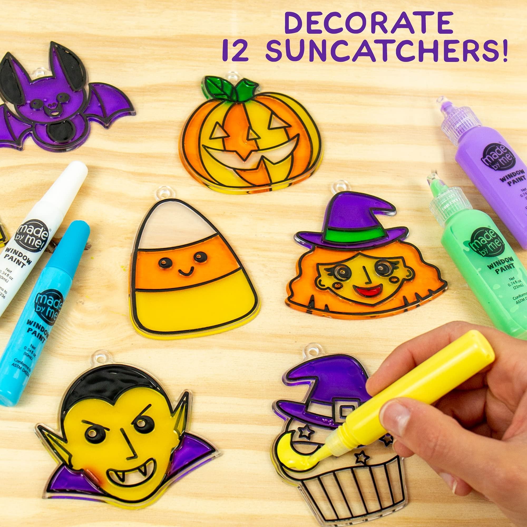 Halloween window art kit with paint tubes and suncatcher frames including bat, pumpkin, candy corn, witch, vampire, and cupcake designs.