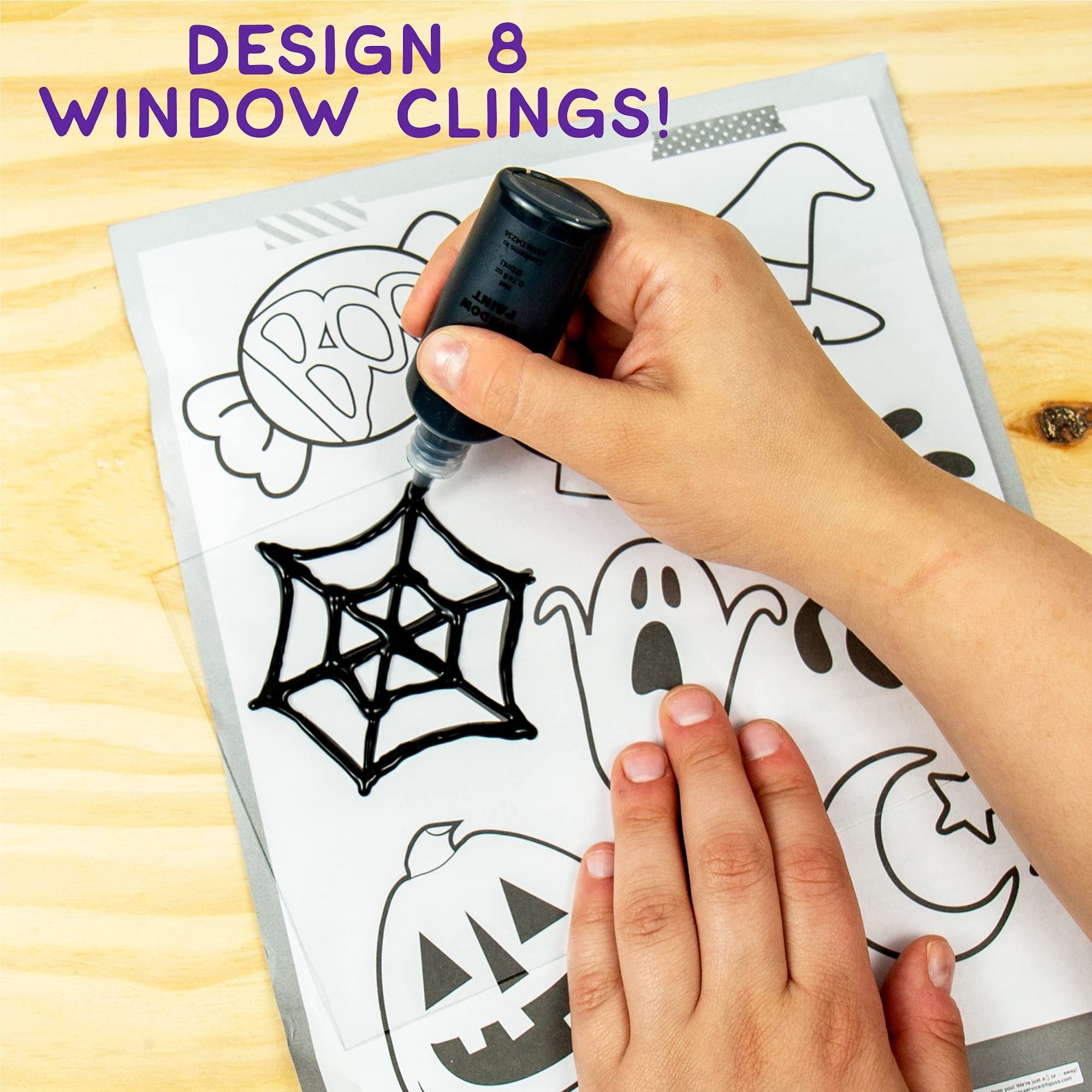 Hand applying black paint to a spider web design on a Halloween window cling template.