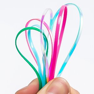 Hand holding colorful plastic lacing cords in heart shapes against a white background