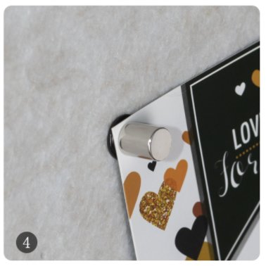 Close-up of a cylindrical magnet holding a decorative card with hearts to a textured surface, numbered 4.