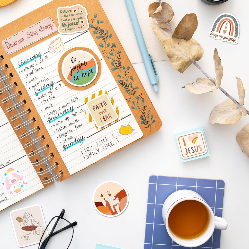 Christian stickers with Bible verses and inspirational quotes arranged on a journal page and around a cup of tea.