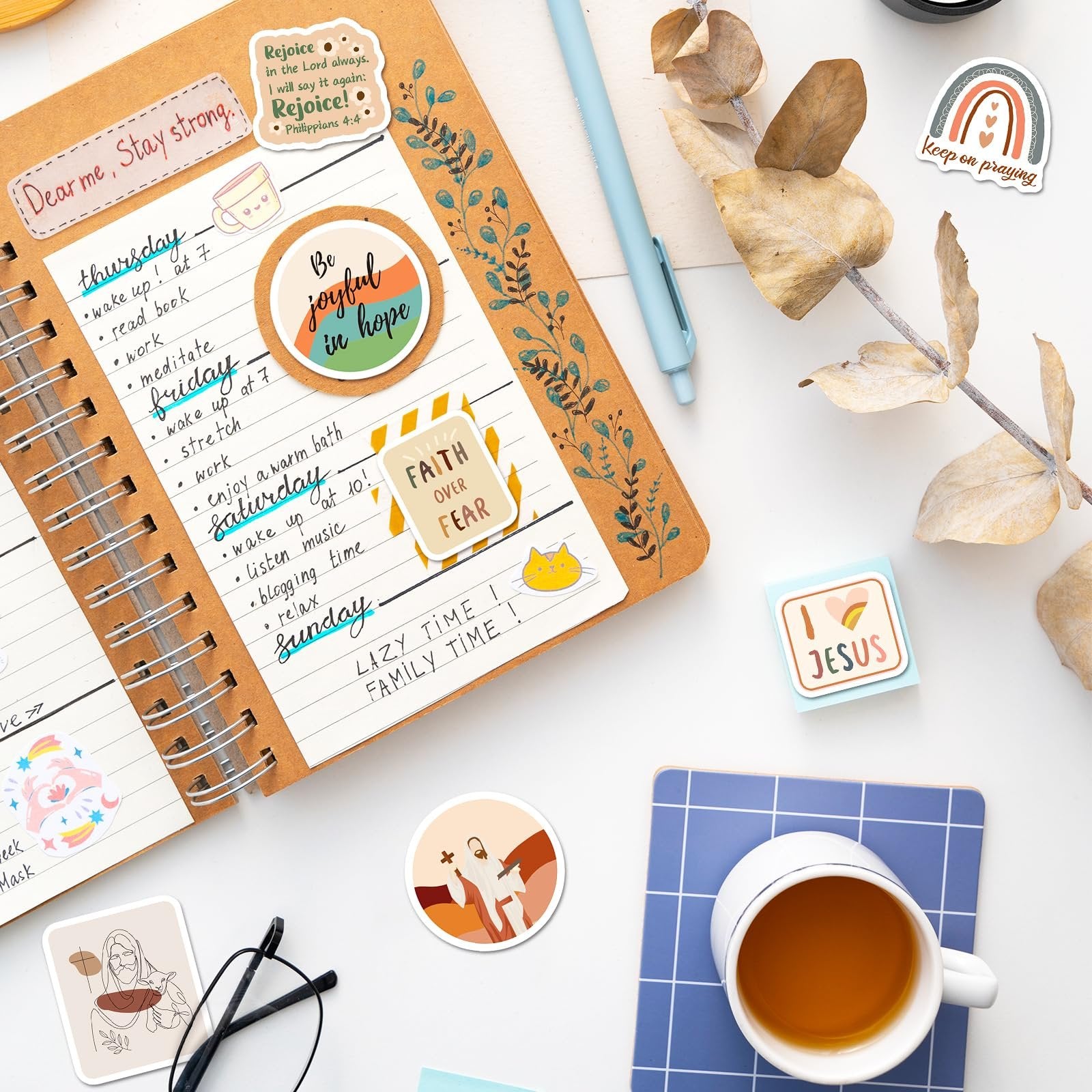 Christian stickers with Bible verses and inspirational quotes arranged on a journal page and around a cup of tea.