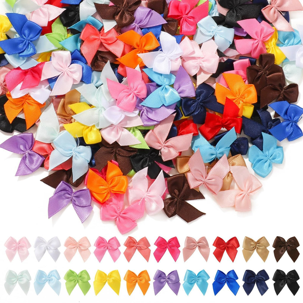 Collection of small, multicolored satin ribbon bows scattered and arranged in rows on a white background.