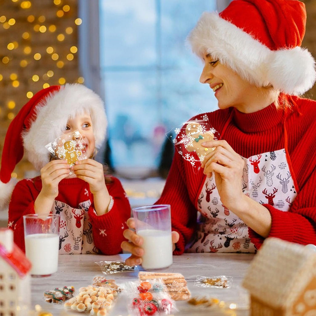Woman and child in Santa hats holding Christmas cookie treat bags with snowflakes