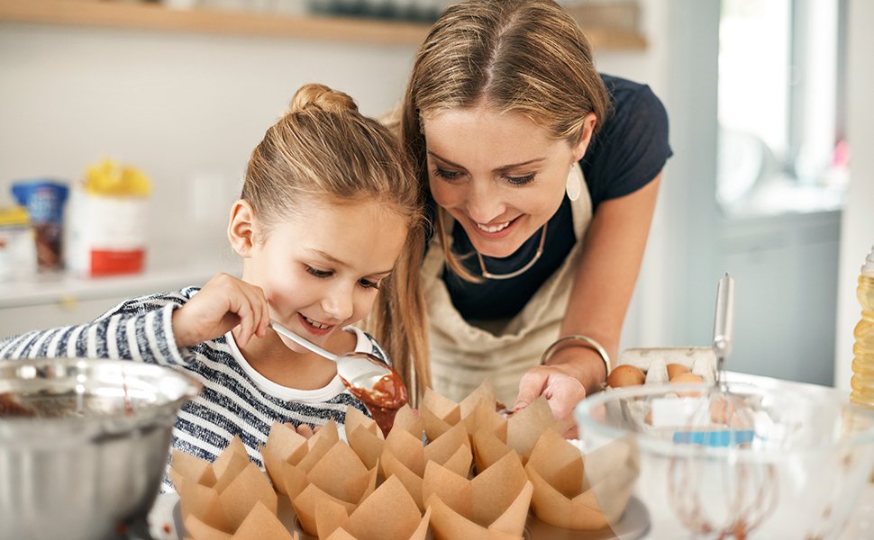 Mother and daughter baking together, preparing tulip cupcake liners for batter.