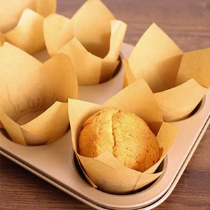 Natural tulip cupcake liners in a muffin tin, one liner holding a baked muffin.