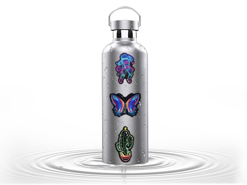Silver water bottle with three holographic stickers: astronaut, butterfly, and cactus, on a white background with water ripples.