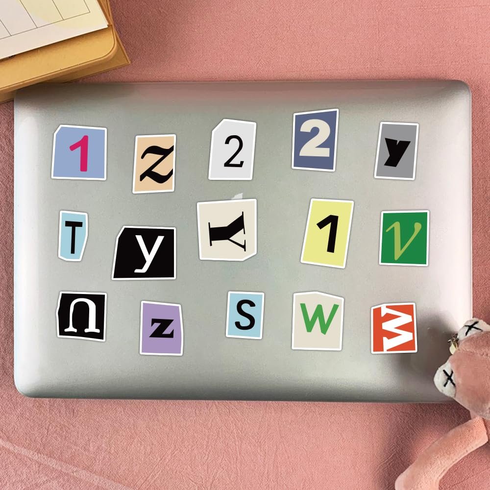 Assorted alphabet and number stickers applied to a laptop lid, including letters like T, Y, U, Z, S, W, M and numbers 1, 2.