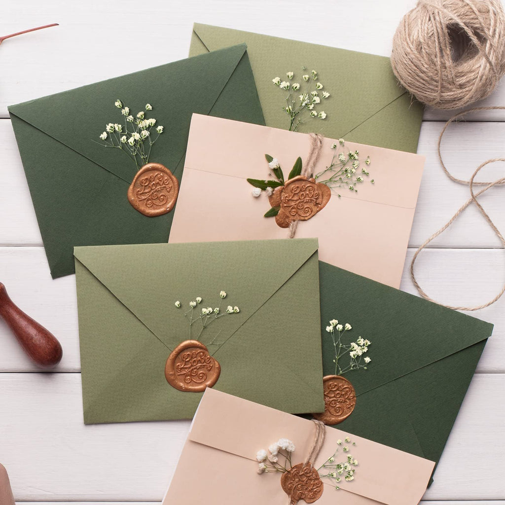 Assortment of green and beige envelopes adorned with dried baby's breath flowers and wax seals.