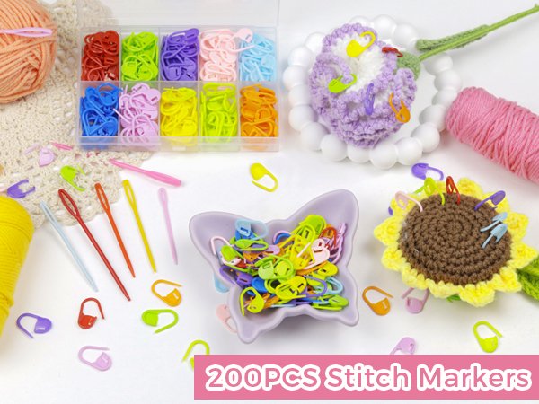 Assorted colorful plastic stitch markers and sewing needles scattered around crochet items and yarn.
