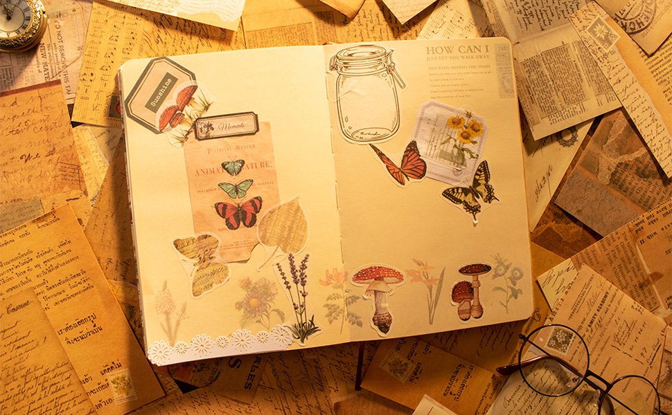 Open journal spread decorated with vintage-style stickers of butterflies, mushrooms, flowers, and a jar, surrounded by aged papers.