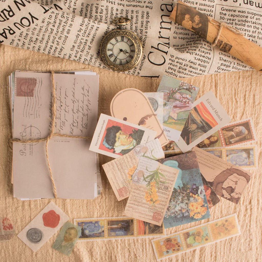 A flat lay of vintage scrapbook stickers, ephemera, and postcards scattered on a textured fabric background, with a pocket watch and wax seals.