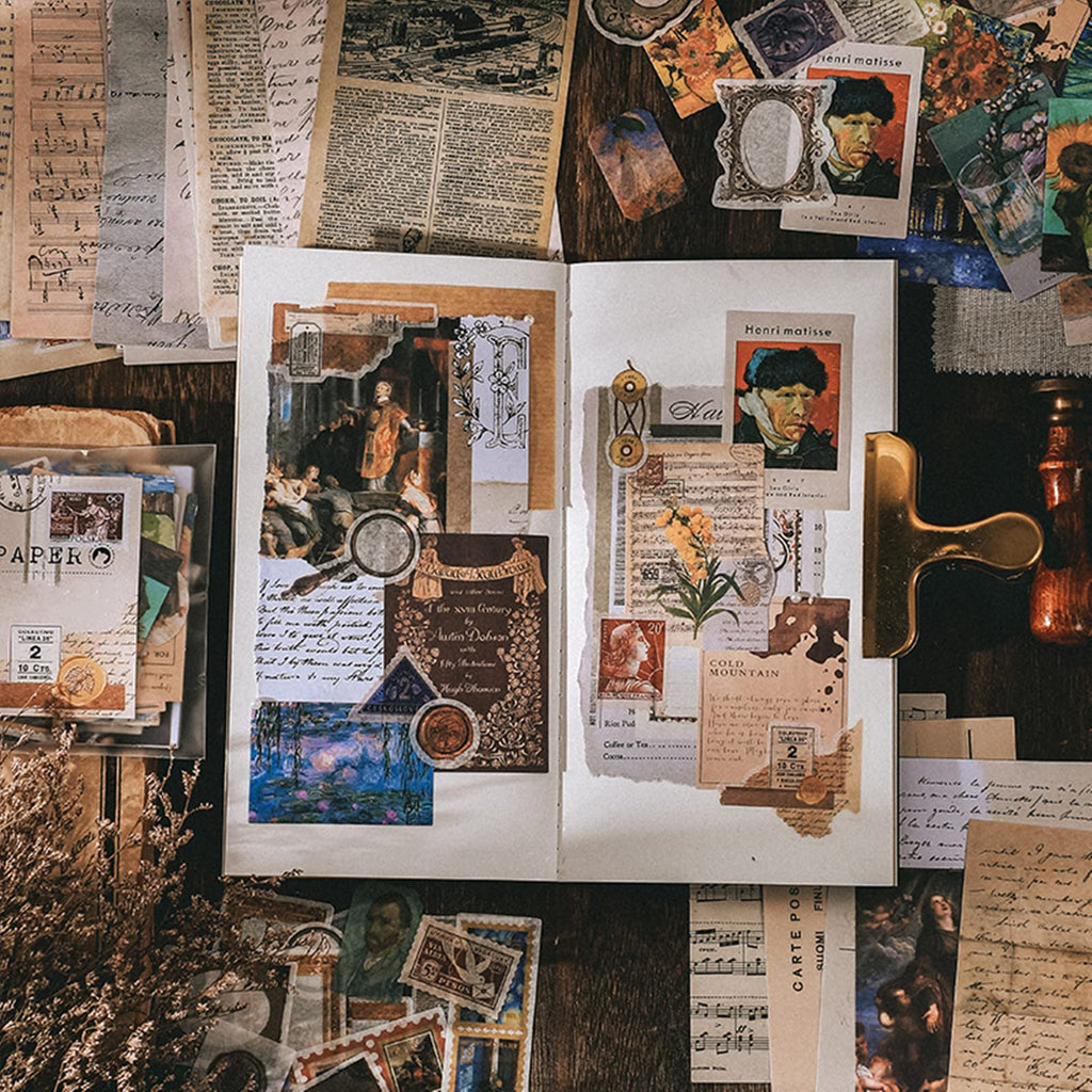 Scrapbooking kit contents laid out on a wooden surface, featuring vintage papers, stickers, and art prints.