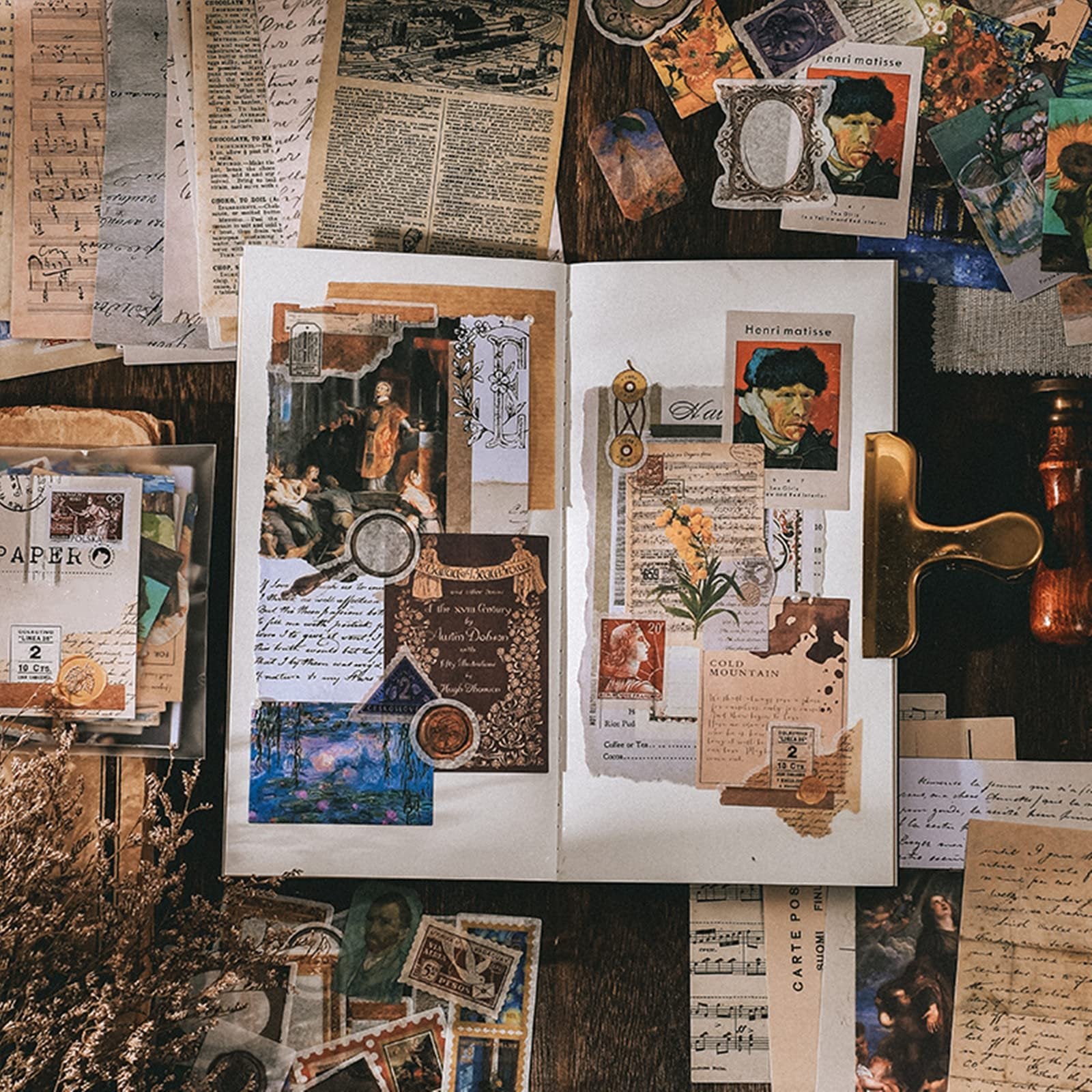 Scrapbooking kit contents laid out on a wooden surface, featuring vintage papers, stickers, and art prints.