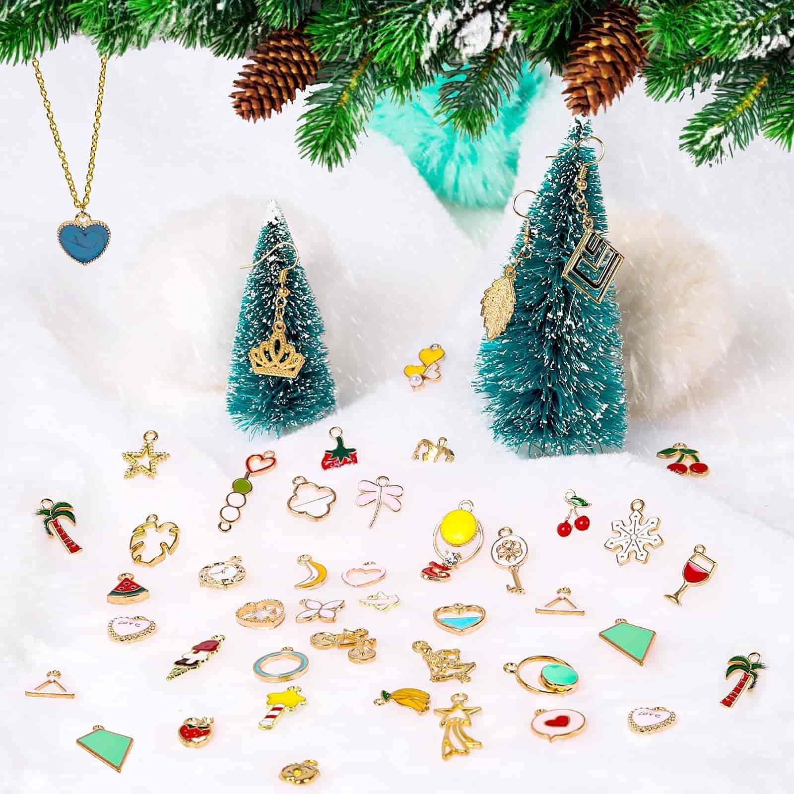 Assortment of jewelry charms including hearts, fruits, animals, and snowflakes, arranged on a snowy surface with miniature Christmas trees and pine branches.
