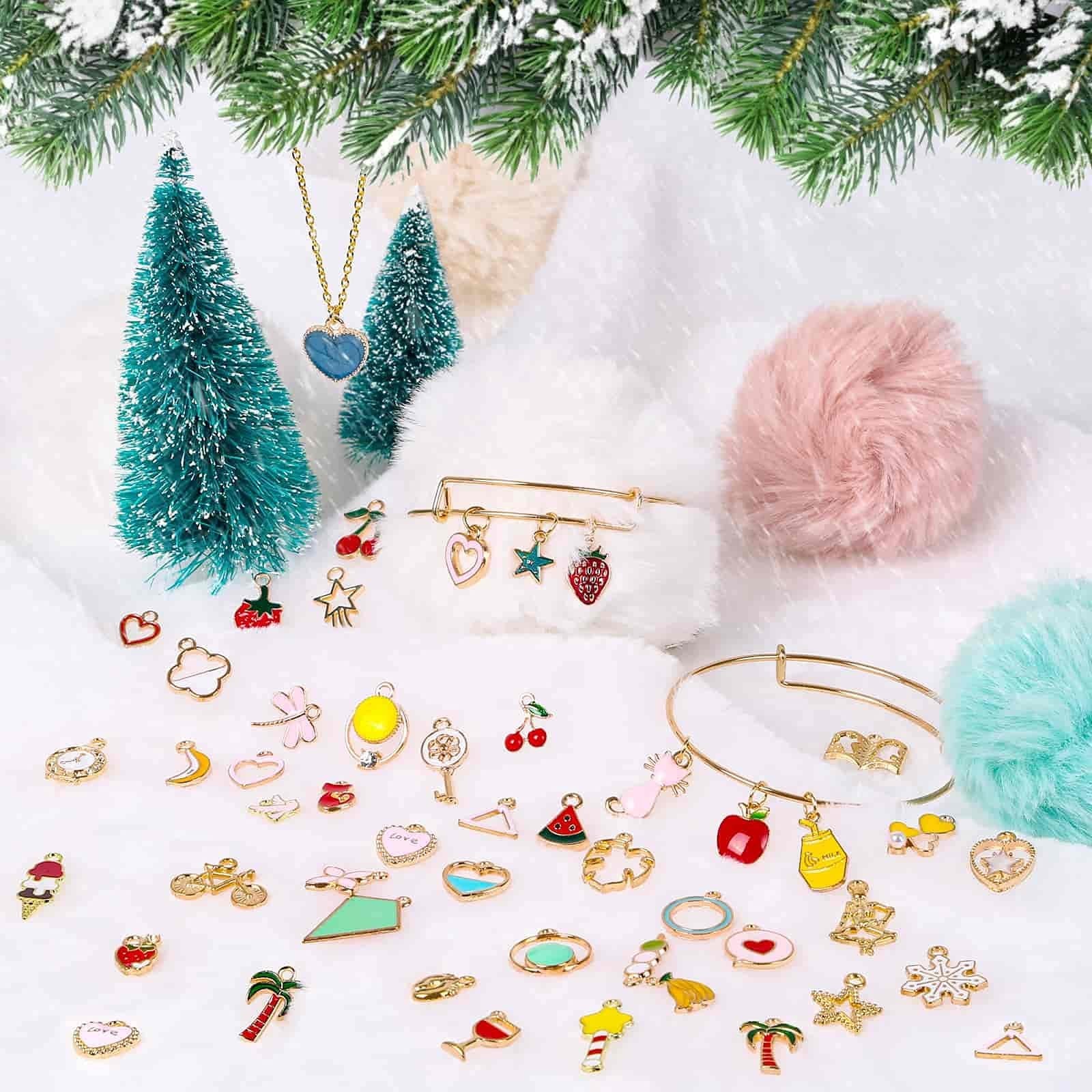 Assortment of colorful enamel and gold-tone jewelry charms scattered on a white surface with festive winter decorations.