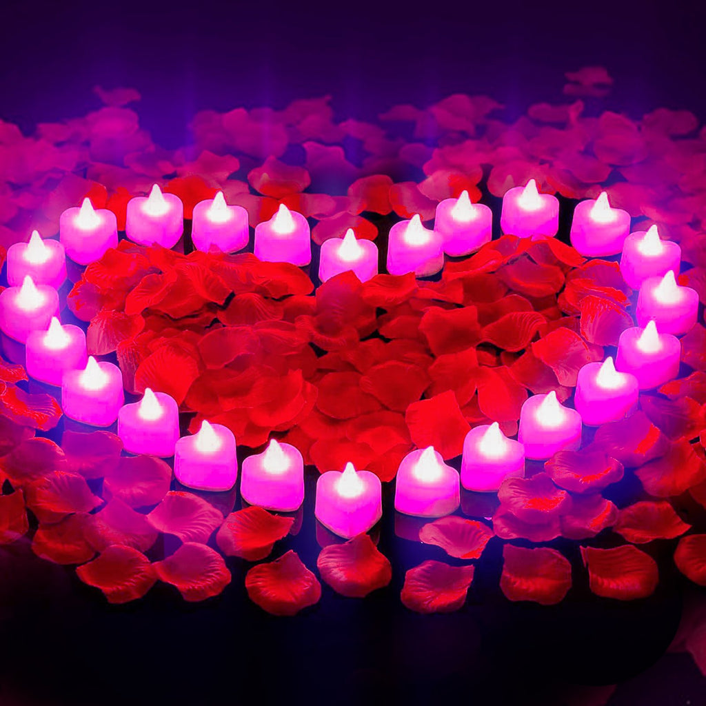 Heart shape arrangement of pink LED tea lights and red rose petals on a dark surface