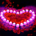 Heart shape arrangement of 24 pink LED tea lights surrounded by red rose petals on a dark background.