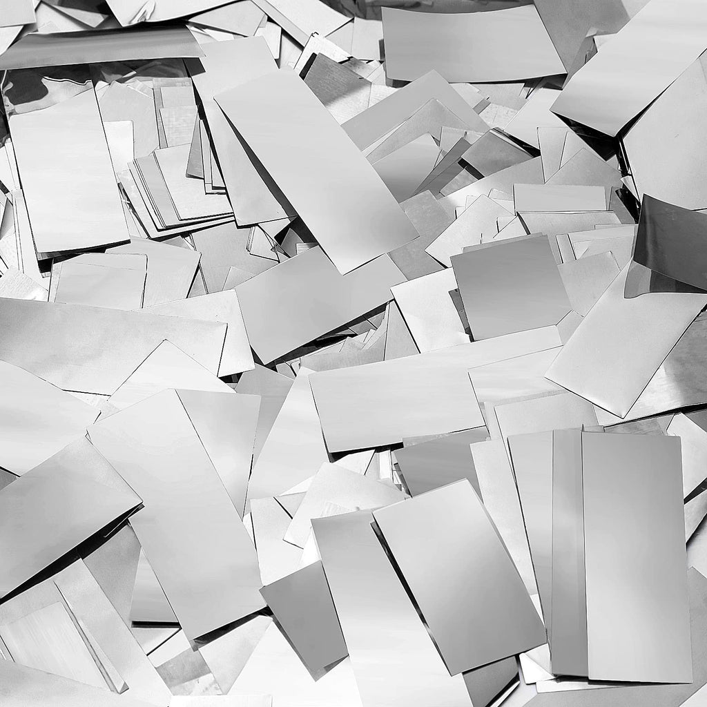 Pile of silver foil confetti pieces scattered across a surface, close-up overhead view.