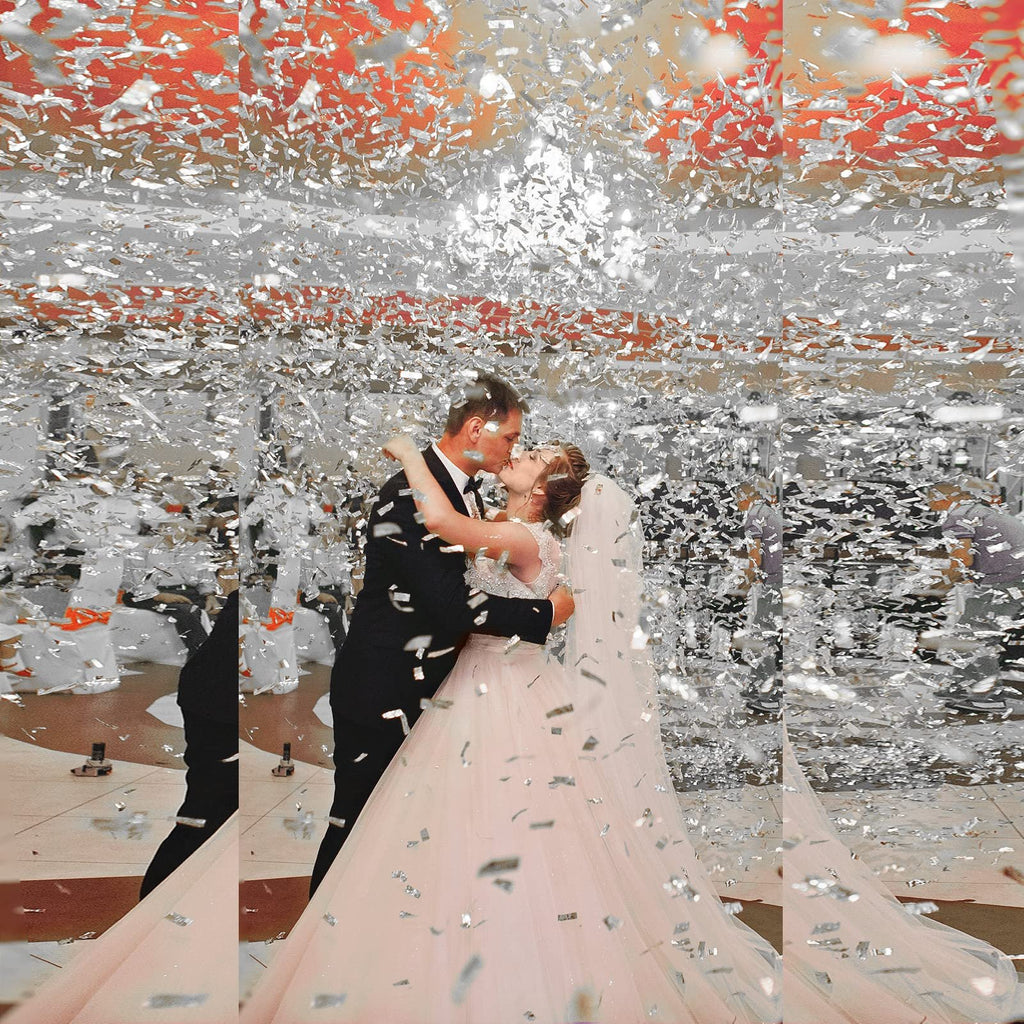 Bride and groom kissing amidst a shower of silver confetti at a wedding reception.