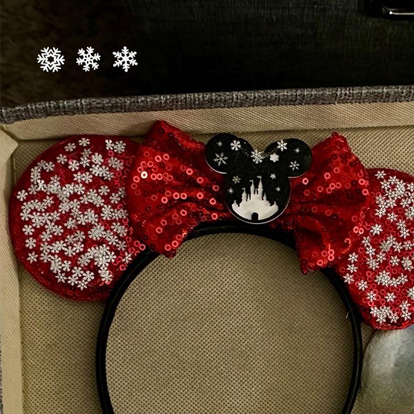 Red sequined Minnie Mouse ears headband with snowflake designs and a black Mickey head bow with castle silhouette