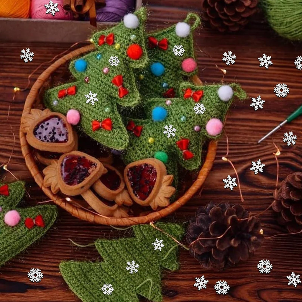 Crocheted Christmas trees with red bows and pom-poms in a basket with cookies, surrounded by pinecones and fairy lights.