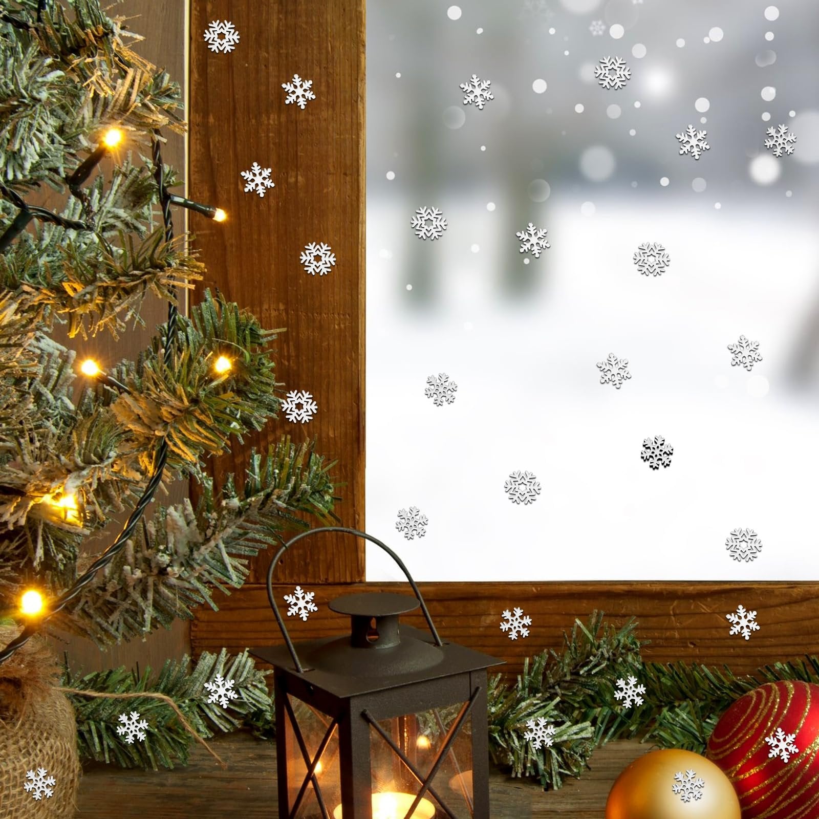 Miniature white metal snowflakes scattered on a wooden surface with a Christmas tree, lantern, and ornaments.