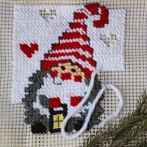 Plastic canvas embroidery kit featuring a gnome with a red and white striped hat and scarf, holding a yellow lantern.