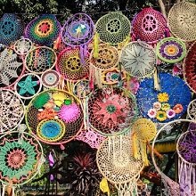 Collection of colorful woven dreamcatchers and macrame wall hangings displayed outdoors.