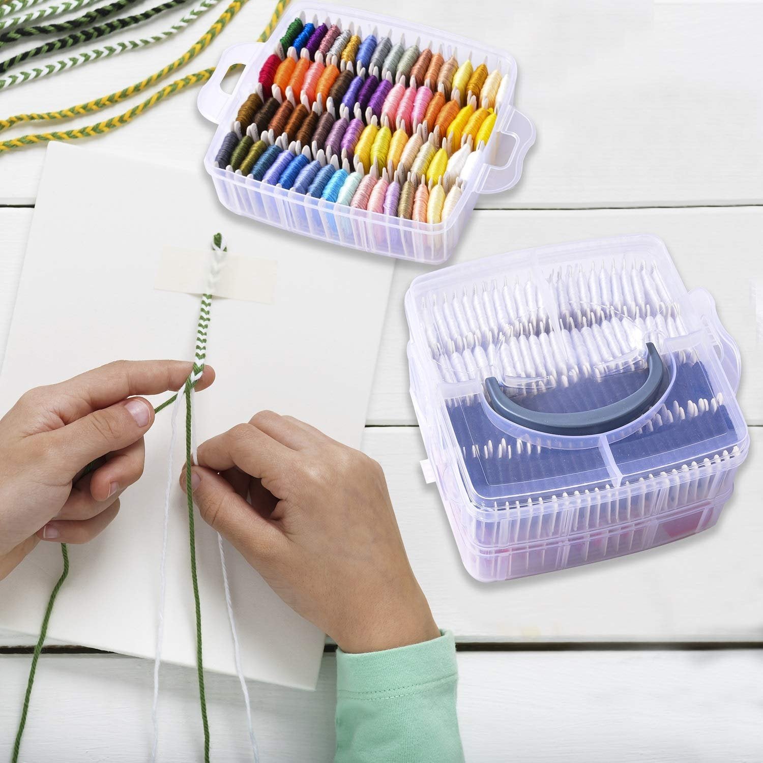 Hands making a friendship bracelet with colorful embroidery floss and organizer boxes.