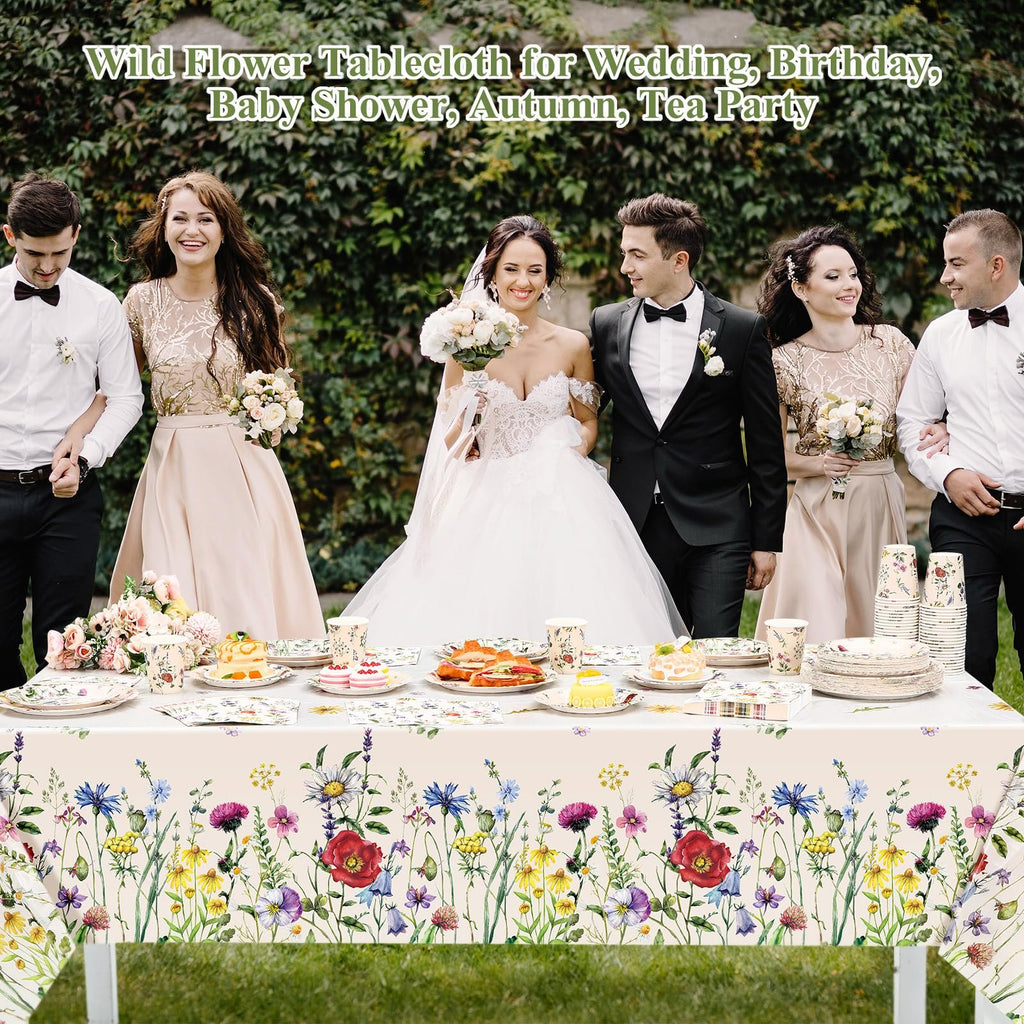 Wedding party gathered around a table with wildflower-themed tableware, including plates, cups, and a tablecloth.