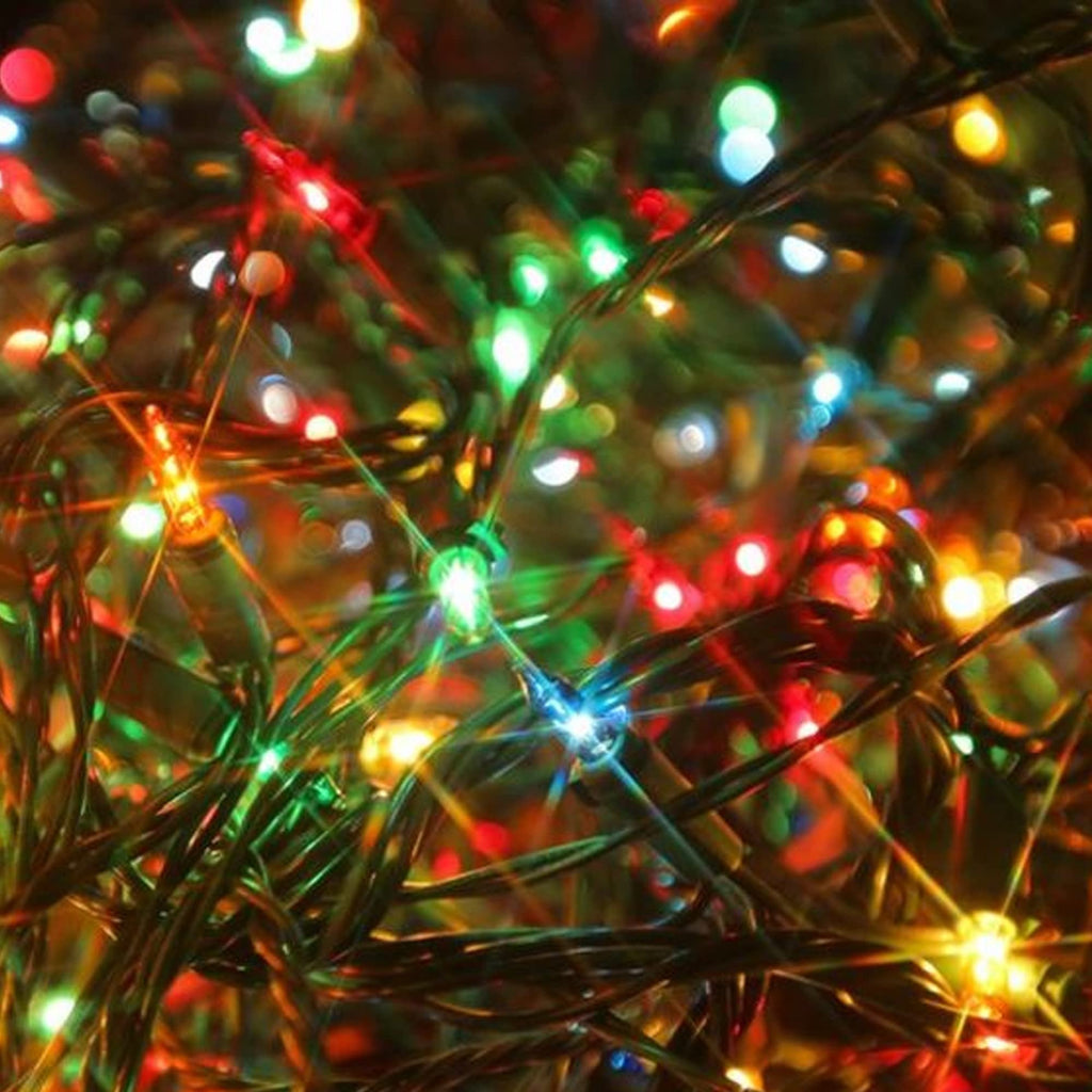 Close-up of multi-colored incandescent mini string lights with green wire, showing red, green, blue, and yellow lights illuminated.