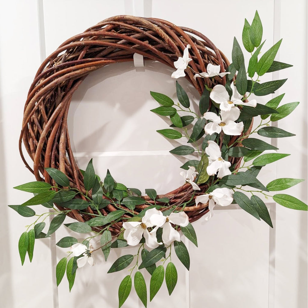Artificial Italian Ruscus greenery wreath with white dogwood flowers on a white door